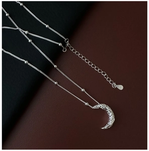 Macro view of S925 sterling silver crescent pendant with hammered texture and bead chain