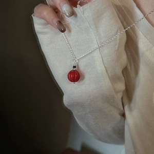 Collier en argent S925 avec perle de cinabre rouge lanterne sur une femme en pull crème