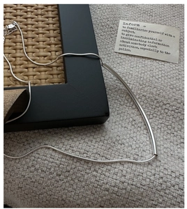 Vue détaillée du collier sourire en argent sterling S925 sur tissu texturé beige
