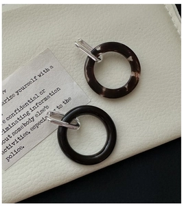 Close-up of minimalist resin hoop earrings in tortoiseshell and glossy black finishes