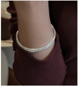 Close-up of S925 sterling silver cuff bracelet with irregular wavy texture on wrist