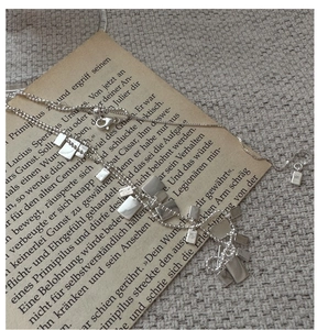 Dettaglio della collana in argento 925 con pendenti quadrati su carta vintage e lino