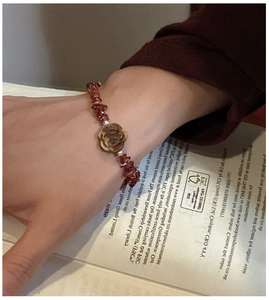 Close-up of a s925 silver bracelet featuring red garnet stones and a carved rose charm