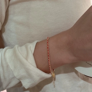 Handmade woven red string bracelet with gold beads and lobster clasp on female wrist