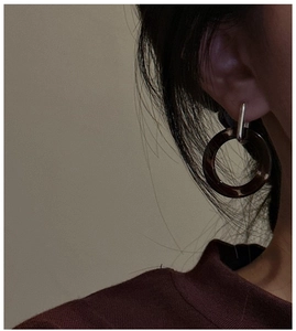 Macro detail of dark amber resin hoop earrings with silver rectangular clasp