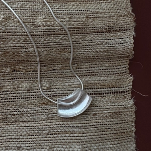 Collier en argent 925 avec pendentif courbé mat sur un fond tressé au style minimaliste