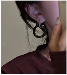 Macro detail of amber-toned resin hoop earring with silver post worn by a model