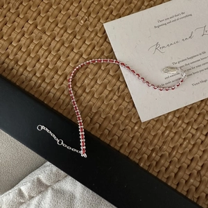 Handmade woven red rope bracelet with 925 silver beads on a rustic display card