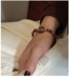 S925 silver bracelet featuring reddish brown garnet stones and a carved flower charm on wrist