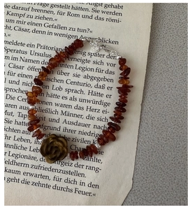 Detail of red agate stone bracelet with carved tiger eye rose on vintage book page