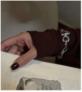 Détail d'un bracelet coeur en argent porté par un mannequin dans un décor vintage