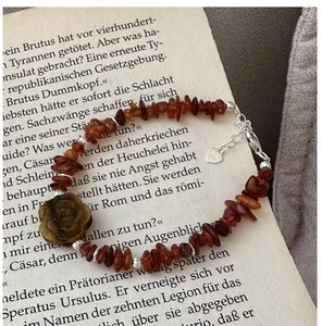 Detail of S925 silver bracelet featuring brown stone beads and carved rose flower charm