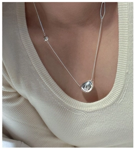 Close-up of S925 silver organic bean pendant necklace worn on a soft knit sweater
