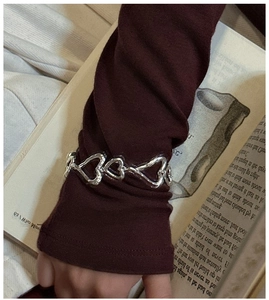 Détail macro du bracelet cœur en argent S925 avec texture fluide sur le poignet d'un modèle