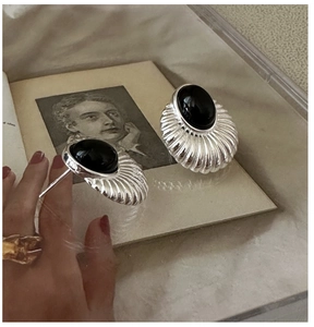 Gros plan sur des boucles d'oreilles rétro en argent avec onyx noir ovale et texture coquille