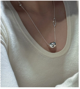Macro detail of S925 sterling silver bean pendant with polished finish on a sweater