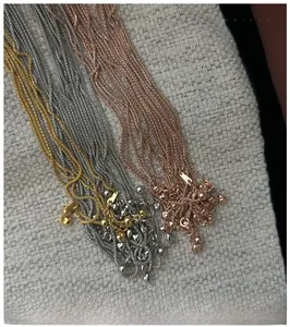 Detail of S925 sterling silver layered chain necklaces in gold, silver, and rose gold