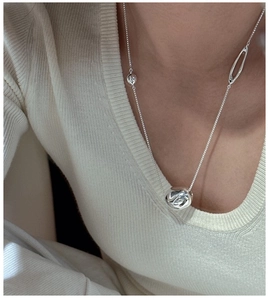 Detailed view of the S925 sterling silver organic pendant on a knit background