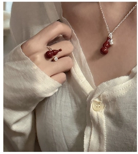 Detail of S925 silver necklace and ring with red gourd design on a model