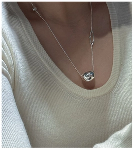 Detail of S925 sterling silver long necklace with irregular bean pendant on a model