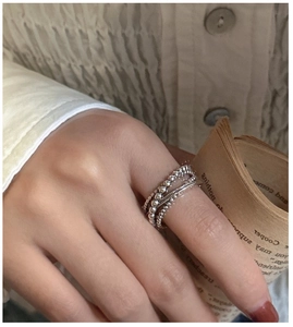 Détail d'une bague triple épaisseur en argent S925 avec perles portée à la main sur un livre