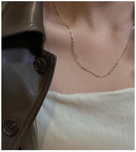Close-up of a delicate rose gold snake chain necklace with bead accents on a model