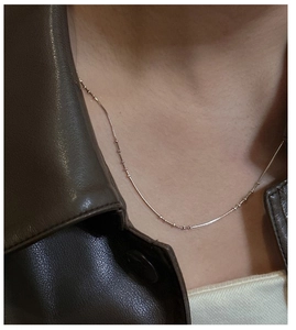 Close-up of minimalist S925 silver snake chain necklace with small rose gold beads