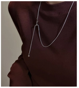 Detail of S925 sterling silver Y-shaped necklace with ball pendant on red sweater