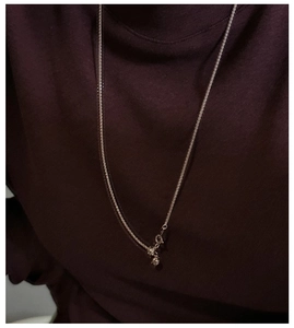Close-up of minimalist S925 sterling silver chain with spring clasp on dark knitwear