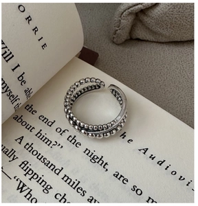 Détail macro d'une bague perlée en argent S925 sur une page de livre rétro
