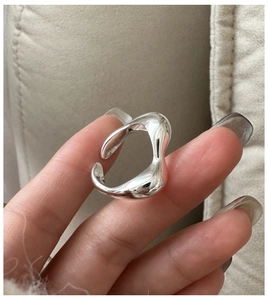Nahaufnahme eines S925 Sterlingsilberrings mit minimalistischem Wellendesign am Finger