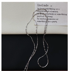 Detailed view of silver S925 snake chain necklace with small beaded accents on duo background