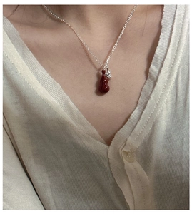 Detail of red agate gourd pendant necklace on silver O-chain worn by female model