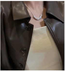 Détail macro du collier avec pendentif arche argenté texturé porté par un mannequin