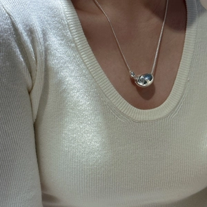 Minimalist S925 sterling silver bean necklace on a cream ribbed sweater with a shiny finish
