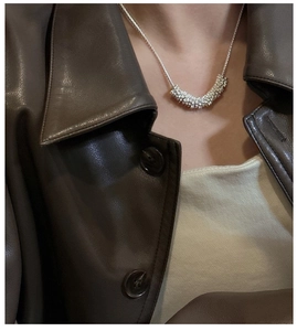Vue détaillée d'un pendentif demi-lune argenté texturé porté par un mannequin élégant