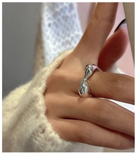 Makro-Detail von silbernem Lava-Ring mit unregelmäßiger Wellentextur am Modellfinger
