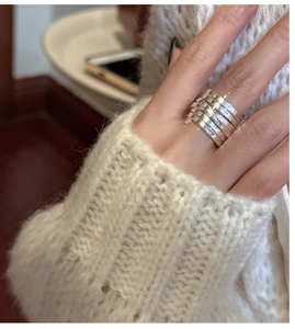 Close-up of layered silver wide-band spring ring styled with knitwear for a chic look