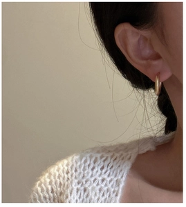 Close-up of minimalist gold hoop earring featuring a smooth polished metallic finish