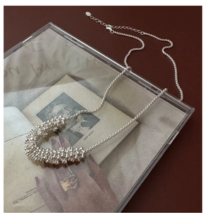 Gros plan d'un collier argenté avec pendentif texturé sur un livre d'art vintage