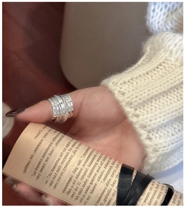 Detail shot of a layered silver spiral ring worn on thumb with minimalist industrial design