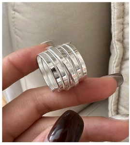 Macro detail of multi-layer wide silver band ring with polished winding line design