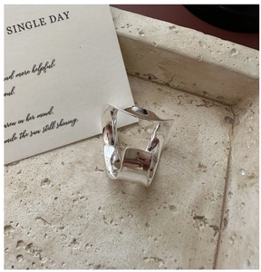 Close-up of irregular wave-shaped S925 sterling silver ring on stone texture tray