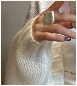 Detailed view of matte S925 sterling silver rectangular ring on finger with cozy knit background
