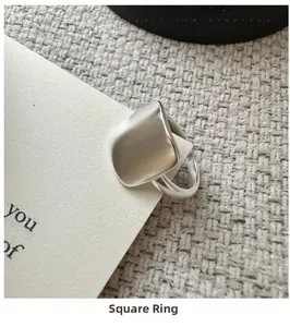 Détail d'une bague carrée mate en argent S925 sur un support de présentation blanc