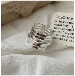 Detail of silver multi-layer spring ring on textured fabric with minimalist aesthetic