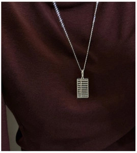 Détail d'un pendentif boulier en argent massif S925 sur un pull en maille rouge
