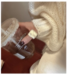 Detail of square ivory pearlescent resin ring on model holding a coffee cup