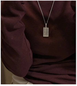Gros plan d'un pendentif boulier en argent S925 porté sur un pull en tricot bordeaux