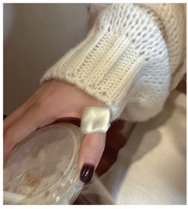 Detail of a thick matte silver square ring worn with a cozy white autumn sweater